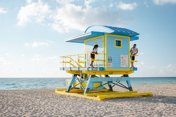 Obraz premium Miami south Beach, youn couple men and woman on the beach during sunrise. Miami beach Floarida