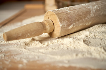 Rolling pin on pastry board sprinkled with flour on wooden  table