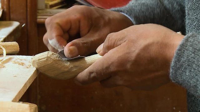 Close-up high-angle still shot of an artisan smoothening a piece of wood using sand paper, Cusco, Peru