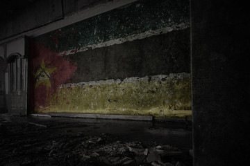 painted flag of mozambique on the dirty old wall in an abandoned ruined house.