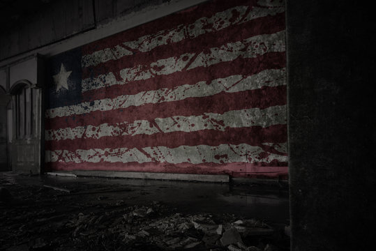 painted flag of liberia on the dirty old wall in an abandoned ruined house.