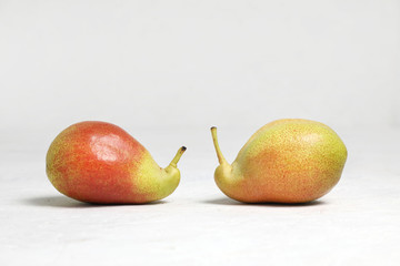 The two curves of the pear .Ugly vegetables , two ripe pears of bizarre shape , lie .  on a white background . fruits are like snails .