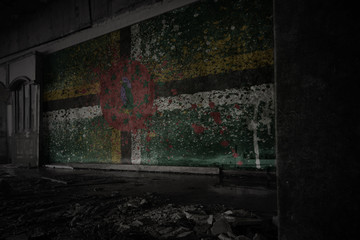painted flag of dominica on the dirty old wall in an abandoned ruined house.