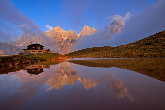 Italy, the mountain group with the mountain Pale di San Martino with Cimon della Pala reflecting in small lake at sunset, Rifugio Baita Giovanni Segantini