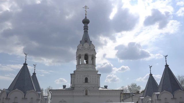 Beautiful church on the background of clouds and the sun, a bell ringer rings the bell on the church bell tower, a church holiday, copy space