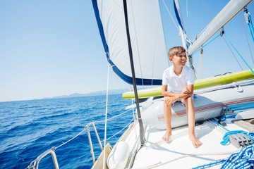 Little boy on board of sailing yacht on summer cruise. Travel adventure, yachting with child on family vacation.