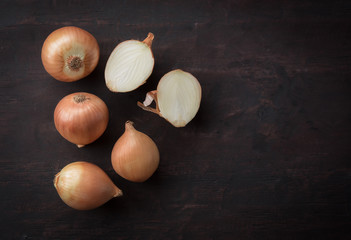 Fresh onions and one sliced onion on wood table