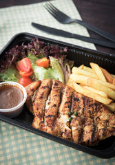 Chicken steak with french fries and sauces in plastic box
