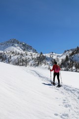 Fototapeta na wymiar Winter sport activity, woman hiking with snowshoes on snow trail on italian alps, Valle d'Aosta.