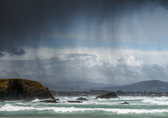 Rain showers blown by the wind between the sea and the cliffs