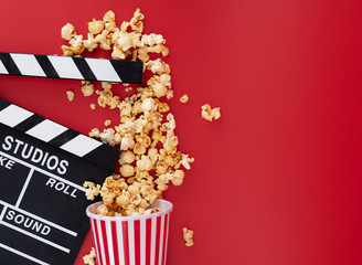 Clapper board with popcorn against red background,Cinema minimal concept,top,view - obrazy, fototapety, plakaty