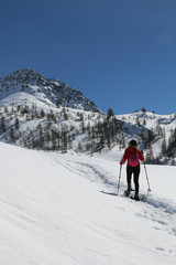 Fototapeta na wymiar Winter sport activity, woman hiking with snowshoes on snow trail on italian alps, Valle d'Aosta.