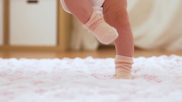 babyhood and people concept - baby's feet in socks stepping on knitted plush blanket