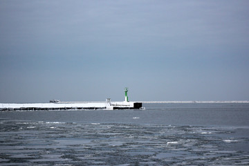 winter port, snowed breakwater and green lighthouse