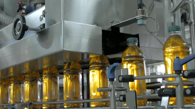 Automatic conveyor belt of production line of juice on beverage plant or factory, modern computerized industrial equipment. Fresh juice in plastic bottles