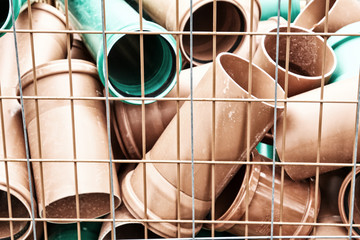 Ein Haufen kurzer Rohre aus Kunststoff liegt in einer Gitterbox.