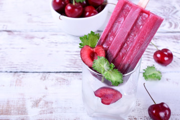Berry popsicle with cherries against the white wooden background