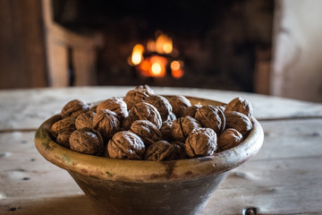 Bowl of natural organic nuts on wooden table near fireplace in ancient village house