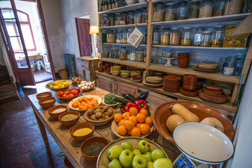 Ancient village cottage cellar with bottles of spices, bowls of healthy natural vegetables and juicy ripe fruits