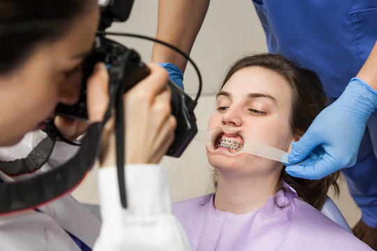 female dentist attending to patient with her assistant, taking pictures of the patient's teeth