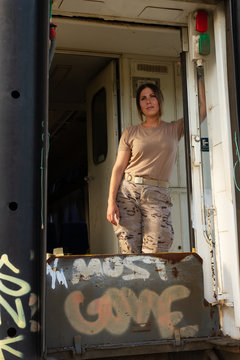 Military woman in uniform looking away and thinking while standing in entrance of grungy transport