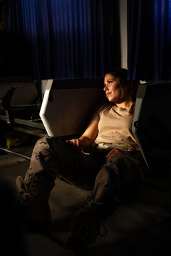 Serious military woman in uniform looking away while sitting on floor of army transport