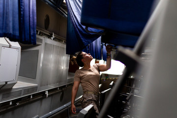 Attractive female soldier looking up while standing inside modern military transport