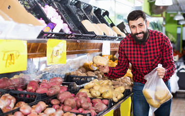 Young male seller offering potatoes