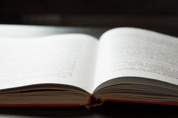 Fototapeta premium An open book is on the table. On a dark background. Close-up