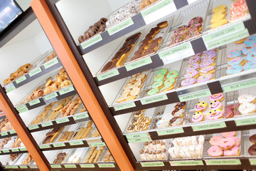 Assorted fresh donuts on display racks at the donut shop.