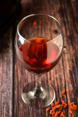 Glass of red wine over rustic, wooden textured table. Dark photo.