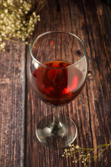 Glass of red wine over rustic, wooden textured table. Dark photo.