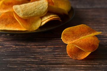 Potato chips over wooden background. Salty crispy snack.