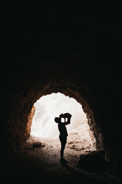 Side view of traveler holding on hands happy playful dog in dark cave in nature
