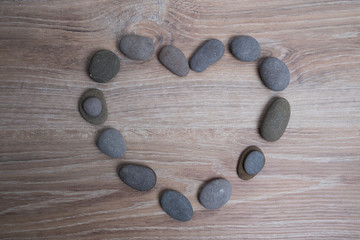 Heart lined with sea stones. River stones in the shape of a heart on a wooden background.