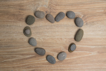 Heart lined with sea stones. River stones in the shape of a heart on a wooden background.
