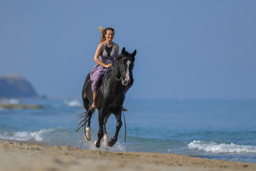 Portrait of a beautiful blond girl galloping on horseback, dissecting waves on the sea beach
