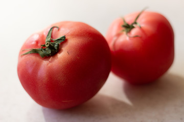 Two red tomatoes on a white background. Two red tomatoes on a white surface