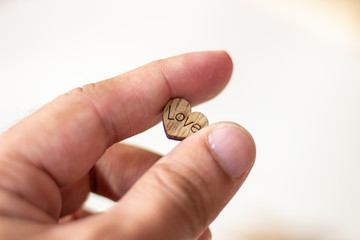 Heart with the inscription love in hand. Wooden heart in hand. Heart in hand. Heart with the inscription love in hand