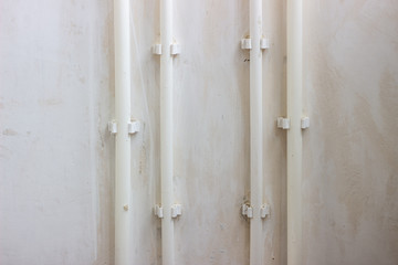 Bends of white water pipes going along the houses wall. White pipes go on a white wall