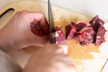 A black knife cuts the meat into pieces. cut the meat into pieces. The mistress of finely cut meat. Cutting meat with a black knife