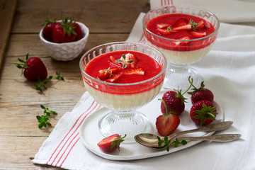 Panna cotta with strawberry sauce and strawberry slices, decorated with thyme leaves. Rustic style.
