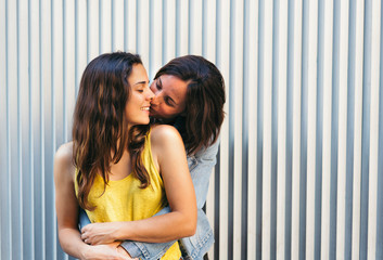 Affectionate woman kissing her happy girlfriend smiling, same sex relationship concept.