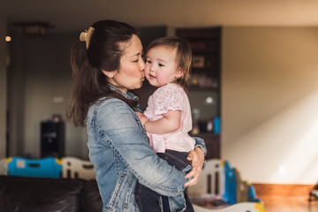 Mother kissing her daughter at home