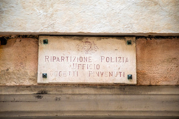 Close-up of an old marble plaque on a wall with the  written "Division Police Department Found Objects" in the historic centre of Genoa, Liguria, Italy