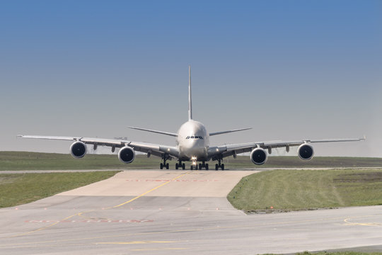 front view of a four engine big jet plane waiting on a taxiway for taking off permission.