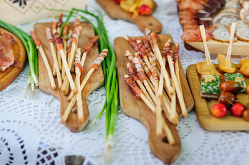 Grissini bread sticks soiled with prosciutto ham on wooden board