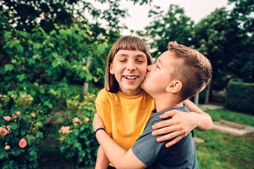 Fototapeta premium Brother kissing and embracing his sister outdoor