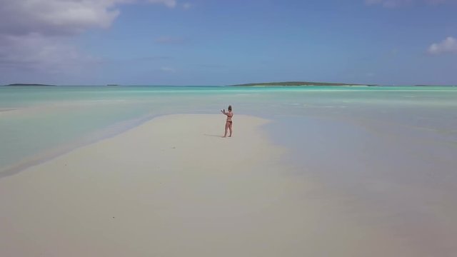 woman walking on a sandbank at the bahamas. exuma island