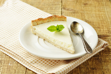 Slice of plain cheesecake on wooden table. Homemade dessert.